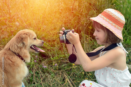 Little girl photographer taking pictures of a dog in nature.