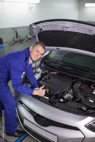 Mechanic leaning on a car while looking at camera
