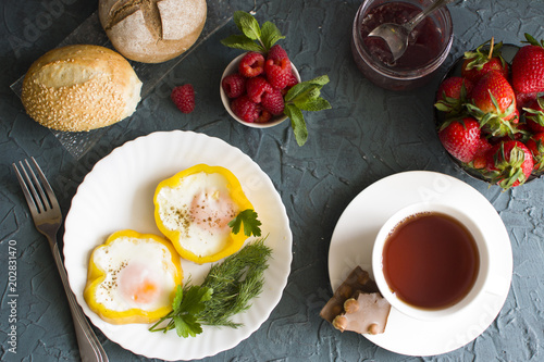 Breakfast with scrambled eggs, raspberries, strawberries and a jar of jam