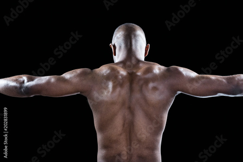 Rear view of muscular athlete with arms outstretched