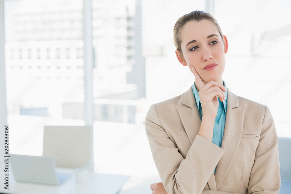 Cute thoughtful chic businesswoman standing in her office Cute thoughtful chic businesswoman standing in her office
