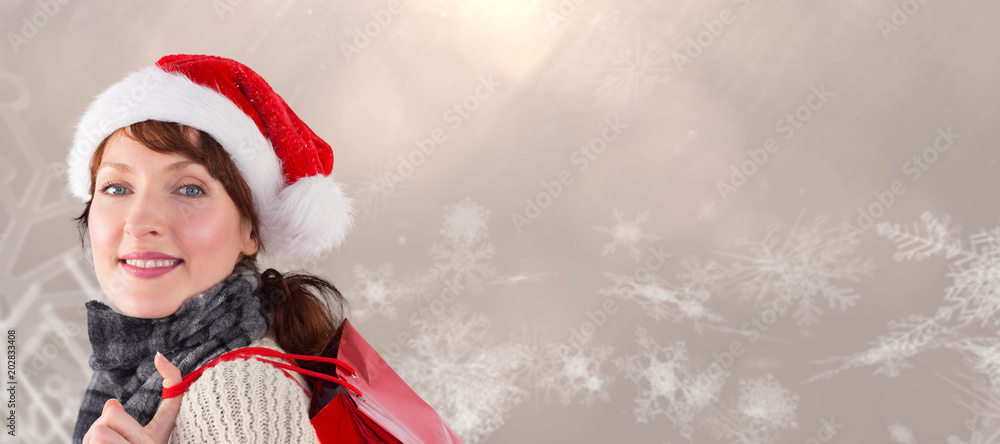 Smiling woman wearing santa hat against image of snowflakes against brown background Smiling woman wearing santa hat against image of snowflakes against brown background