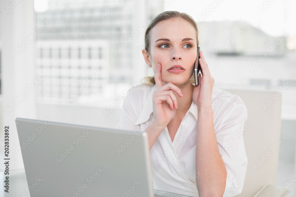 Thoughtful businesswoman using laptop and making a call Thoughtful businesswoman using laptop and making a call