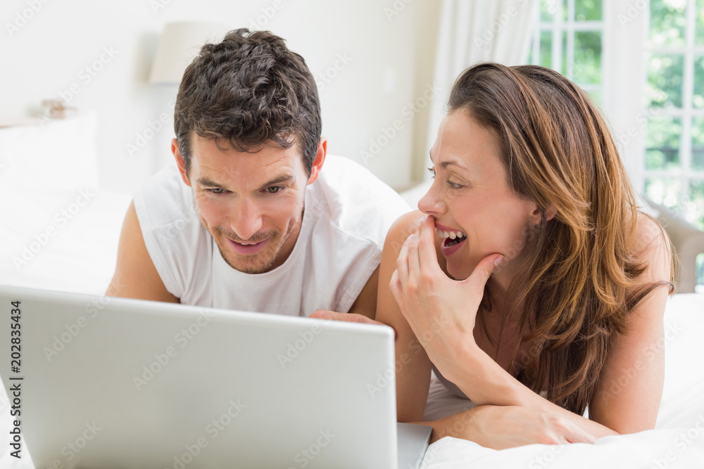 Happy couple using laptop in bed Happy couple using laptop in bed