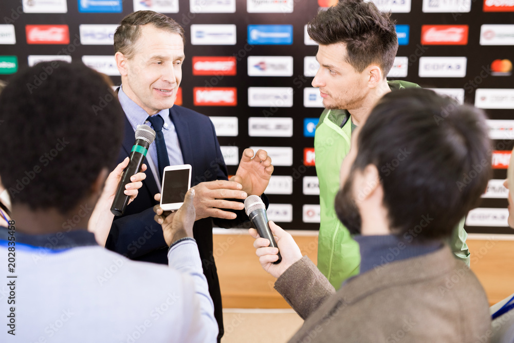 Φωτογραφία Portrait of young professional sportsman and his mature manager answering questi