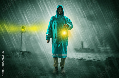 Man at the coast coming in raincoat with glowing lantern concept 