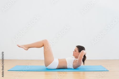 Sporty young woman doing sits up at fitness studio