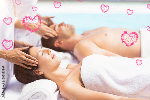 Red Hearts against couple receiving head massage from masseur