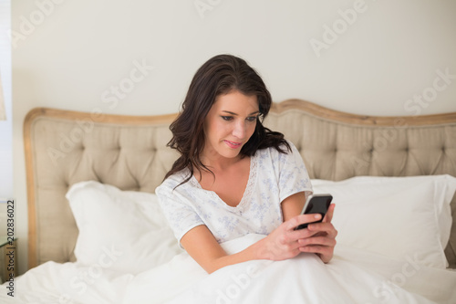Concentrated pretty brown haired woman typing on a mobile phone