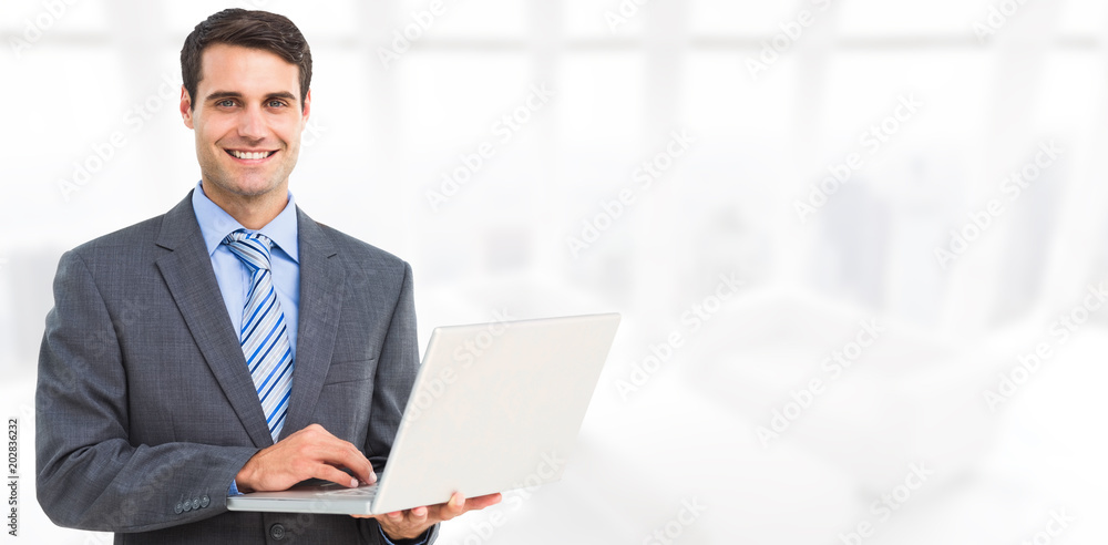 Portrait of smiling businessman using laptop against modern room overlooking city Portrait of smiling businessman using laptop against modern room overlooking city