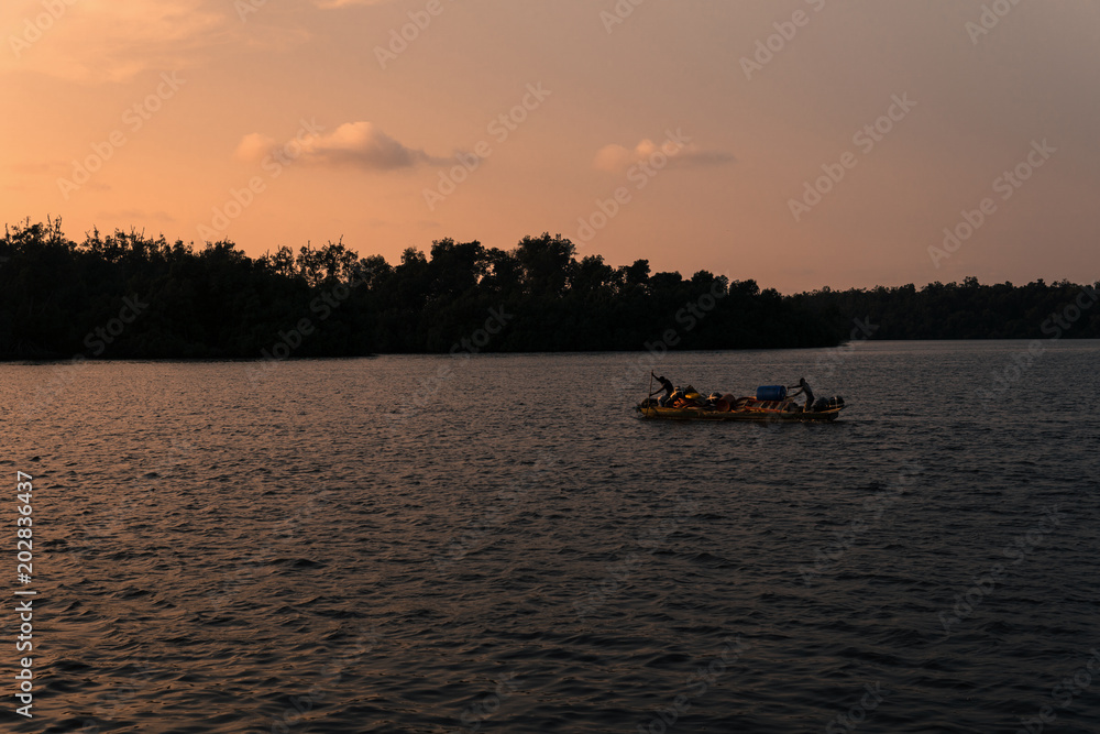 Silhouette of african unrecognizable fishermen boat or canoe at sea with beautiful sky.