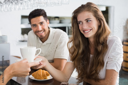 Hand giving coffee to a couple at coffee shop