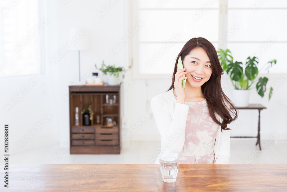 部屋で電話をする女性 部屋で電話をする女性