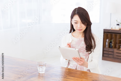 部屋でタブレットを見る女性