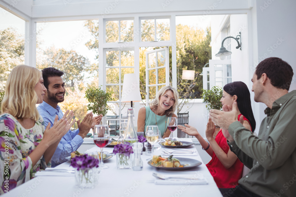Group of friends interacting with each other while having meal together Group of friends interacting with each other while having meal together