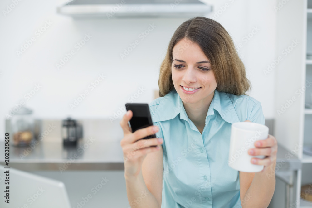 Beautiful young woman using her smartphone holding a cup Beautiful young woman using her smartphone holding a cup