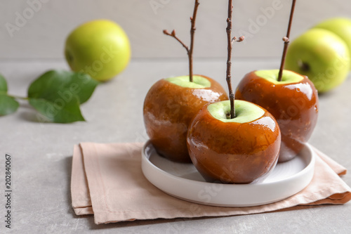Plate with delicious green caramel apples on table