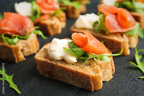 Tasty sandwiches with fresh sliced salmon fillet on table