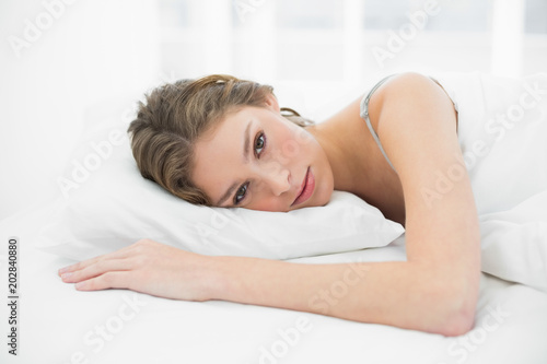 Beautiful relaxed woman lying on her bed under the cover