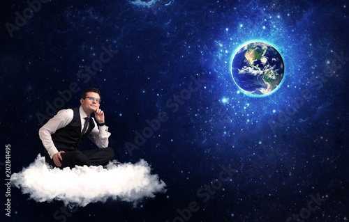 Caucasian businessman sitting on a white fluffy cloud looking and wondering at planet earth