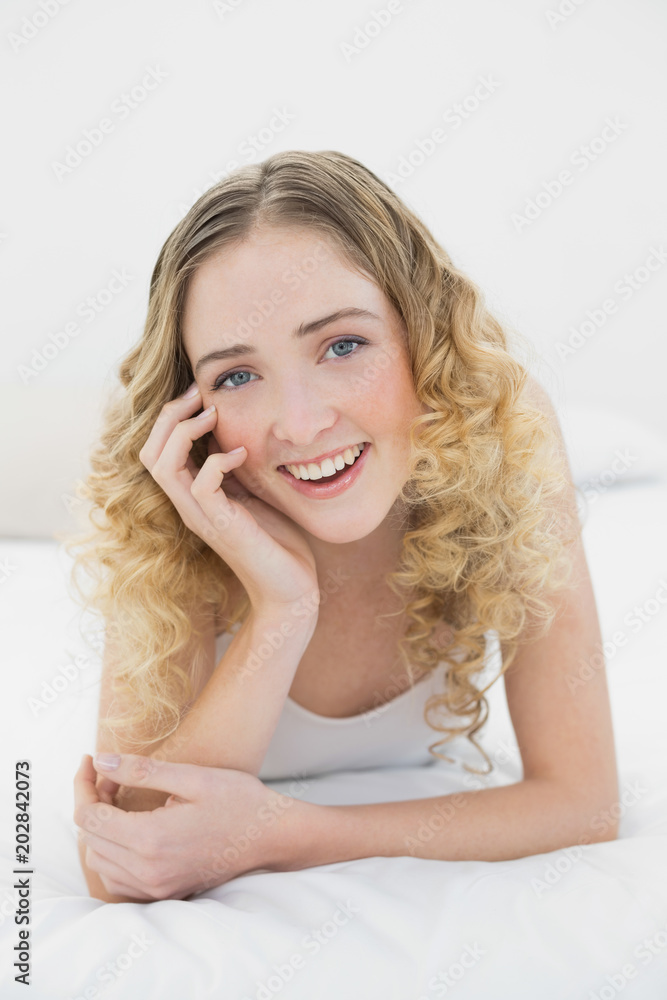 Pretty smiling blonde lying on bed looking at camera Pretty smiling blonde lying on bed looking at camera