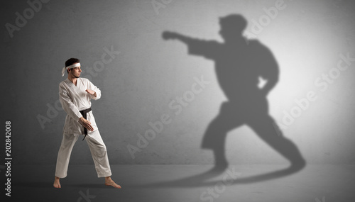 Young karate man confronting with his own shadow 