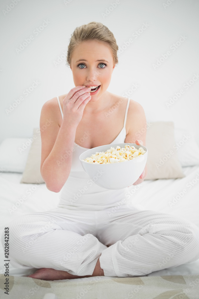 Natural cheerful blonde eating popcorn on bed Natural cheerful blonde eating popcorn on bed