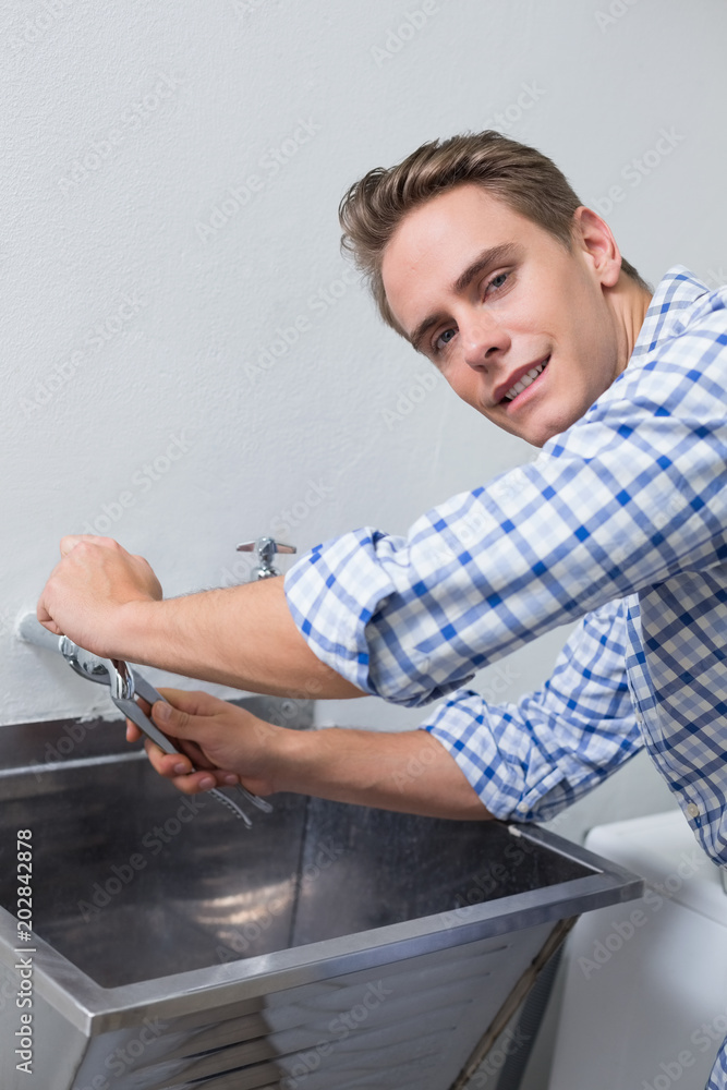 Portrait of plumber fixing water tap with pliers Portrait of plumber fixing water tap with pliers