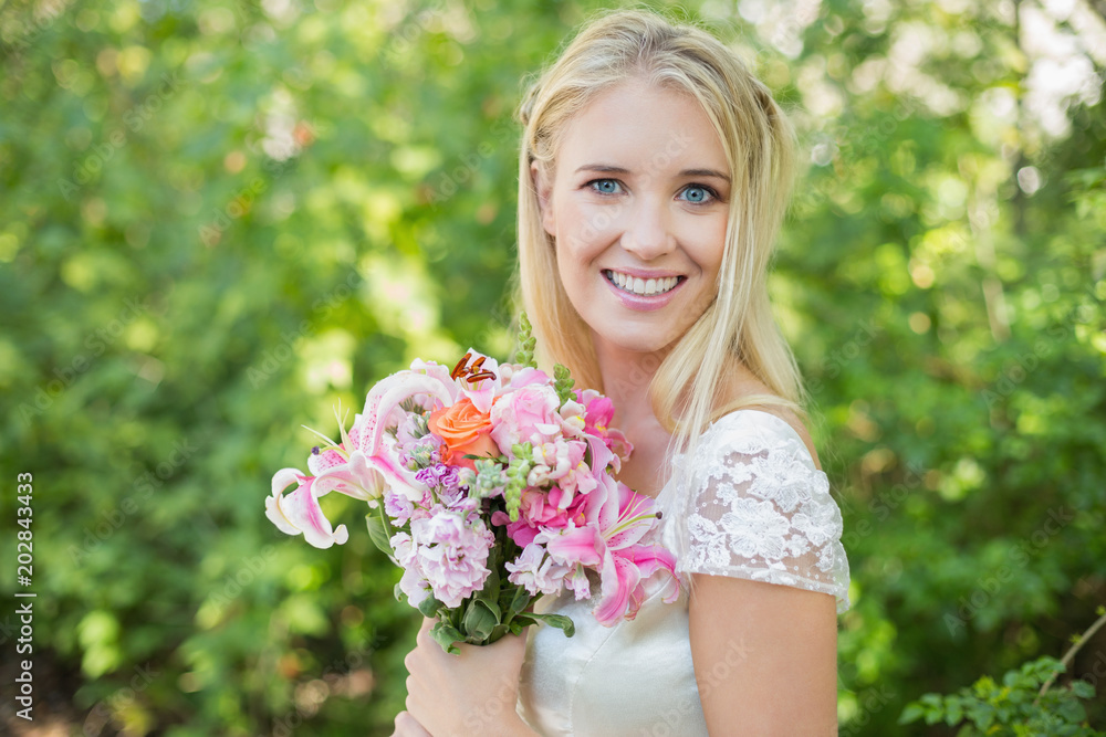 Blonde smiling bride holding bouquet looking at camera Blonde smiling bride holding bouquet looking at camera
