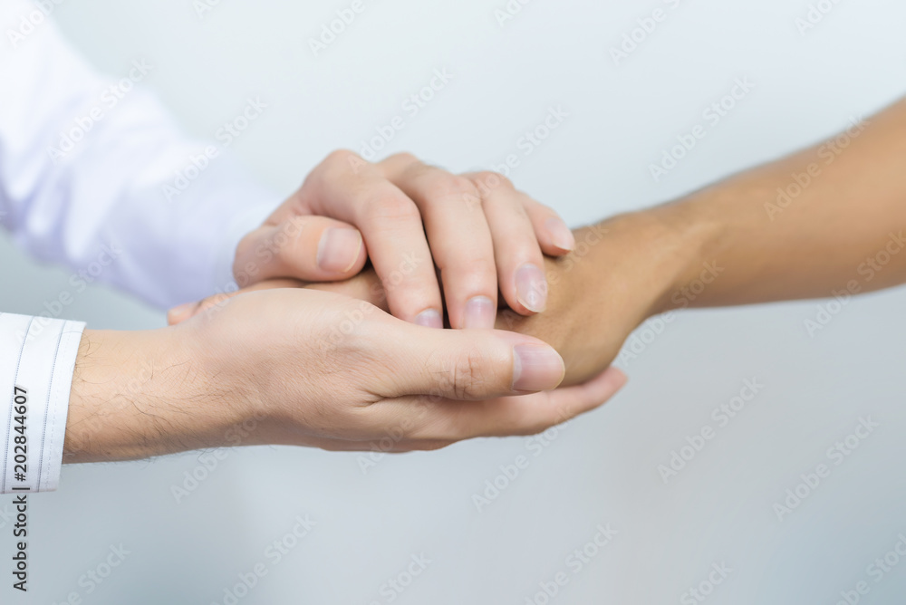 Two people holding hands for comfort. Doctor consoling relatives of patients in hospital concept Two people holding hands for comfort. Doctor consoling relatives of patients in hospital concept