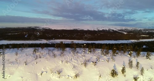 Snowy fjeld, C4k aerial sideway view of a tunturi fell, infront of luostotunturi mountain, in arctic tundra, on a sunny winter morning dusk, Pyha-luosto national park, Pelkosenniemi, Lapland, Finland photo