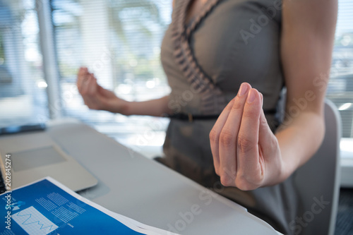 Mid section of female executive performing yoga at desk © WavebreakmediaMicro