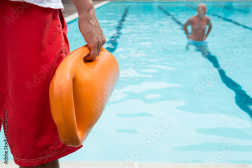 Lifeguard holding rescue buoy at poolside