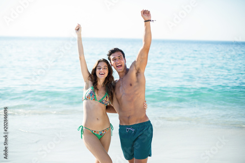 Couple standing with arms raised at beach