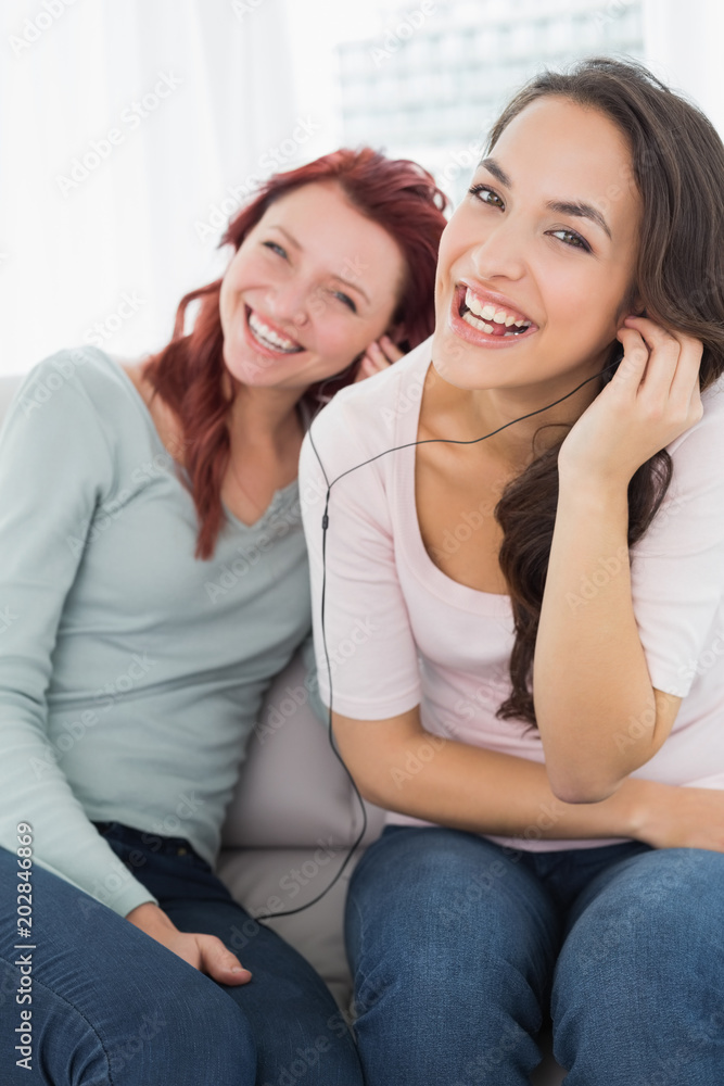 Friends listening music through earphones together at home