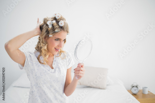 Cheerful gorgeous blonde wearing hair curlers posing