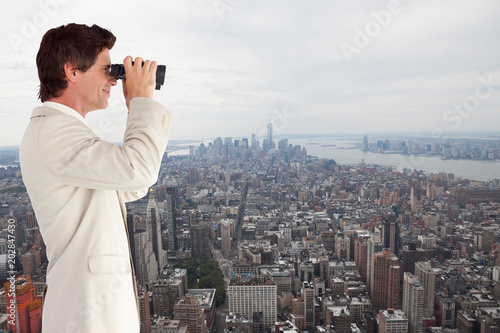 Businessman using binoculars against new york