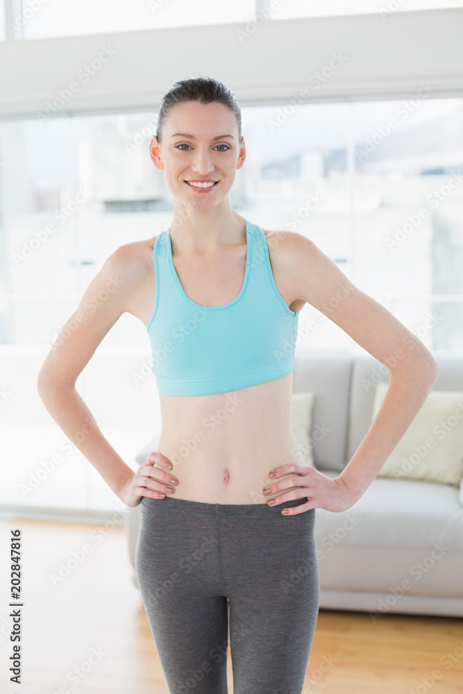 Toned woman with hands on hips in fitness studio