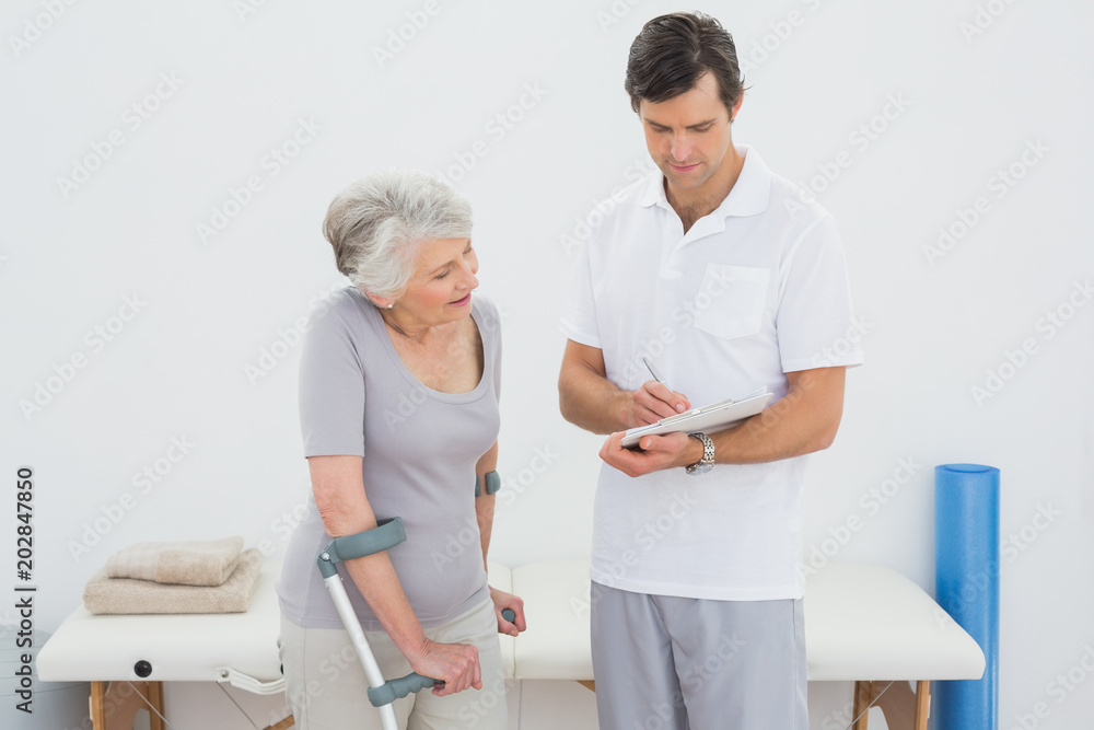 Therapist discussing reports with a disabled senior patient Therapist discussing reports with a disabled senior patient