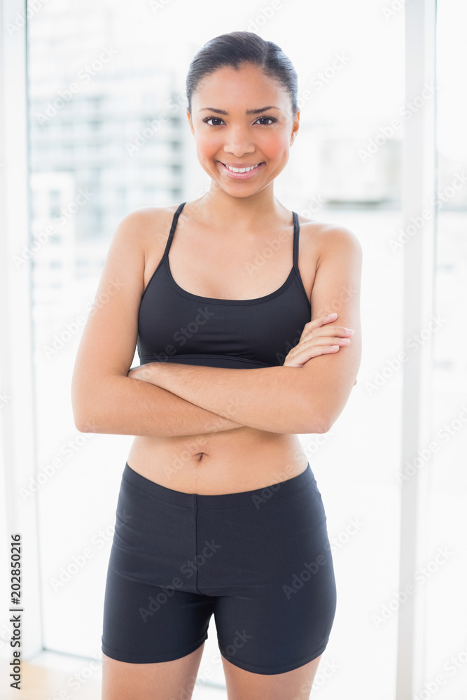 Smiling dark haired model in sportswear posing with crossed arms