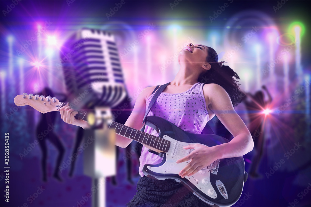 Fototapeta Pretty girl playing guitar against digitally generated cool nightlife background