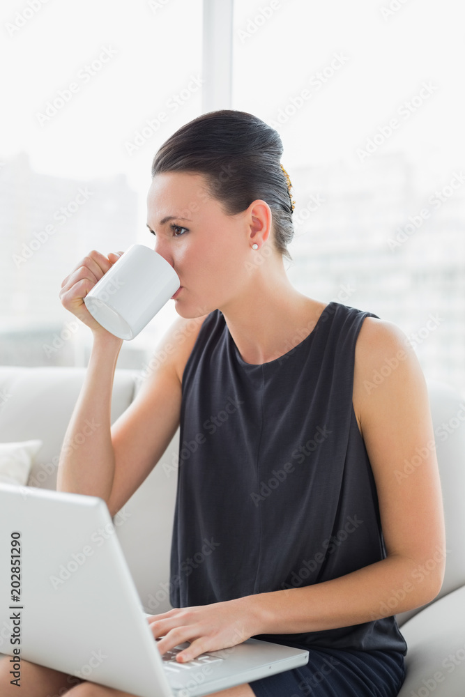 Beautiful well dressed woman using laptop while drinking coffee Beautiful well dressed woman using laptop while drinking coffee