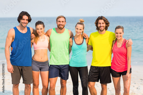 Happy friends standing with arm around at beach