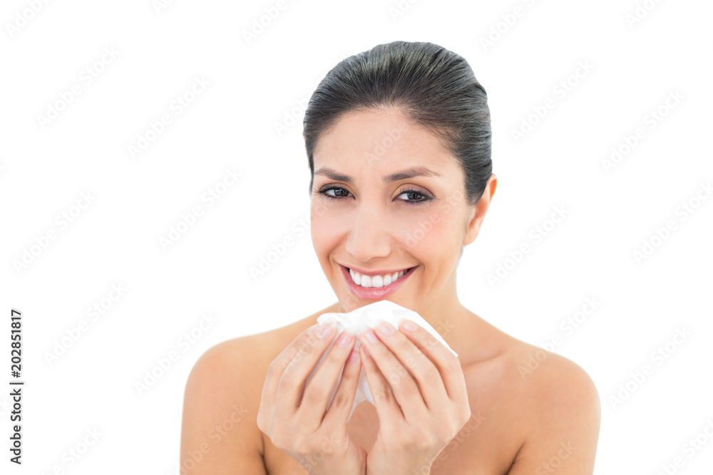 Sick brunette holding a tissue and smiling at camera Sick brunette holding a tissue and smiling at camera