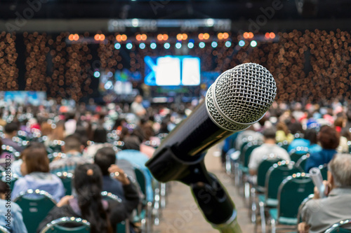 Microphone over the Abstract blurred photo of conference hall or seminar room in Exhibition Center background with Speakers on the stage and attendee background, Business meeting and education concept