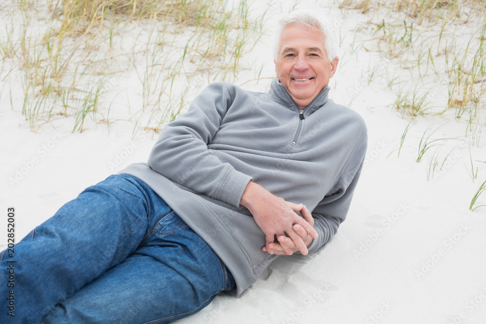 Smiling senior man relaxing on sand at beach