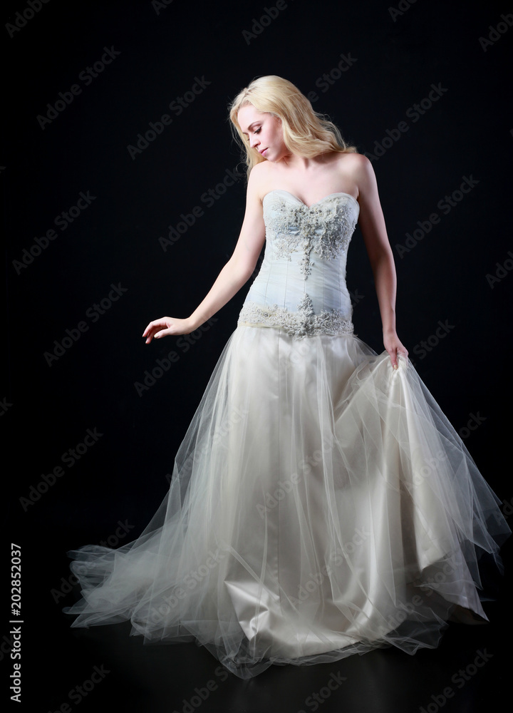 full length portrait of woman wearing white bridal gown. standing poison black studio background. full length portrait of woman wearing white bridal gown. standing poison black studio background.