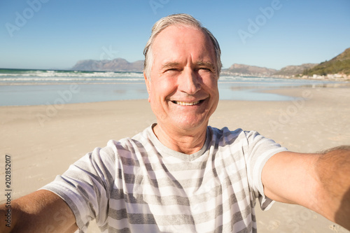 Portrait of smiling senior man standing at beach