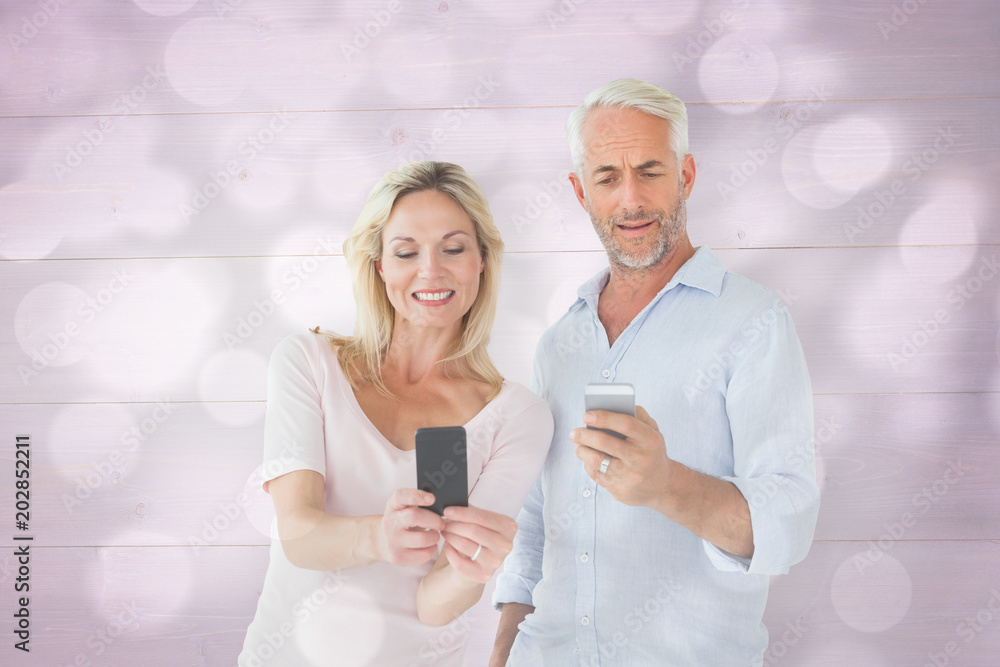 Happy couple texting on their smartphones against light circles on grey background Happy couple texting on their smartphones against light circles on grey background