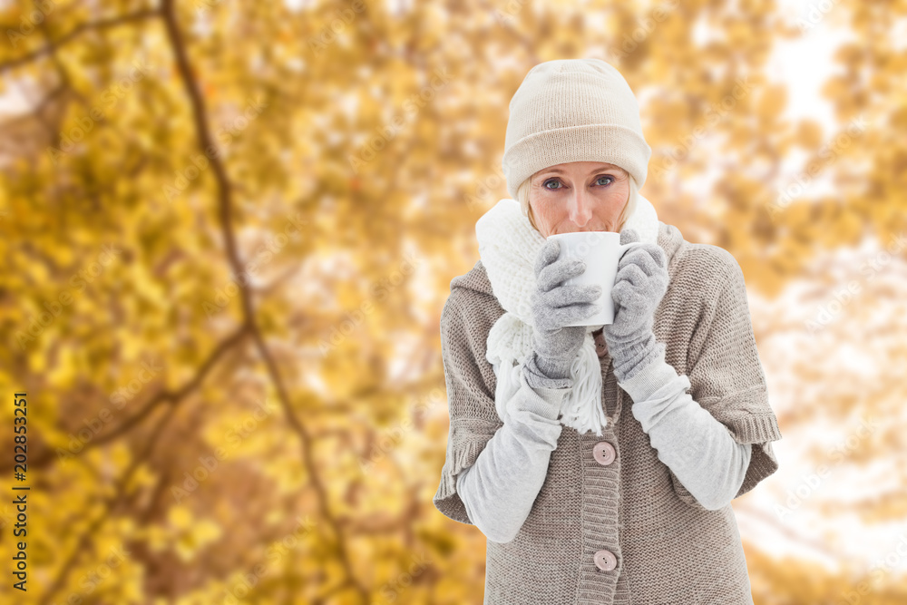 Woman in warm clothing holding mugs against tranquil autumn scene in forest